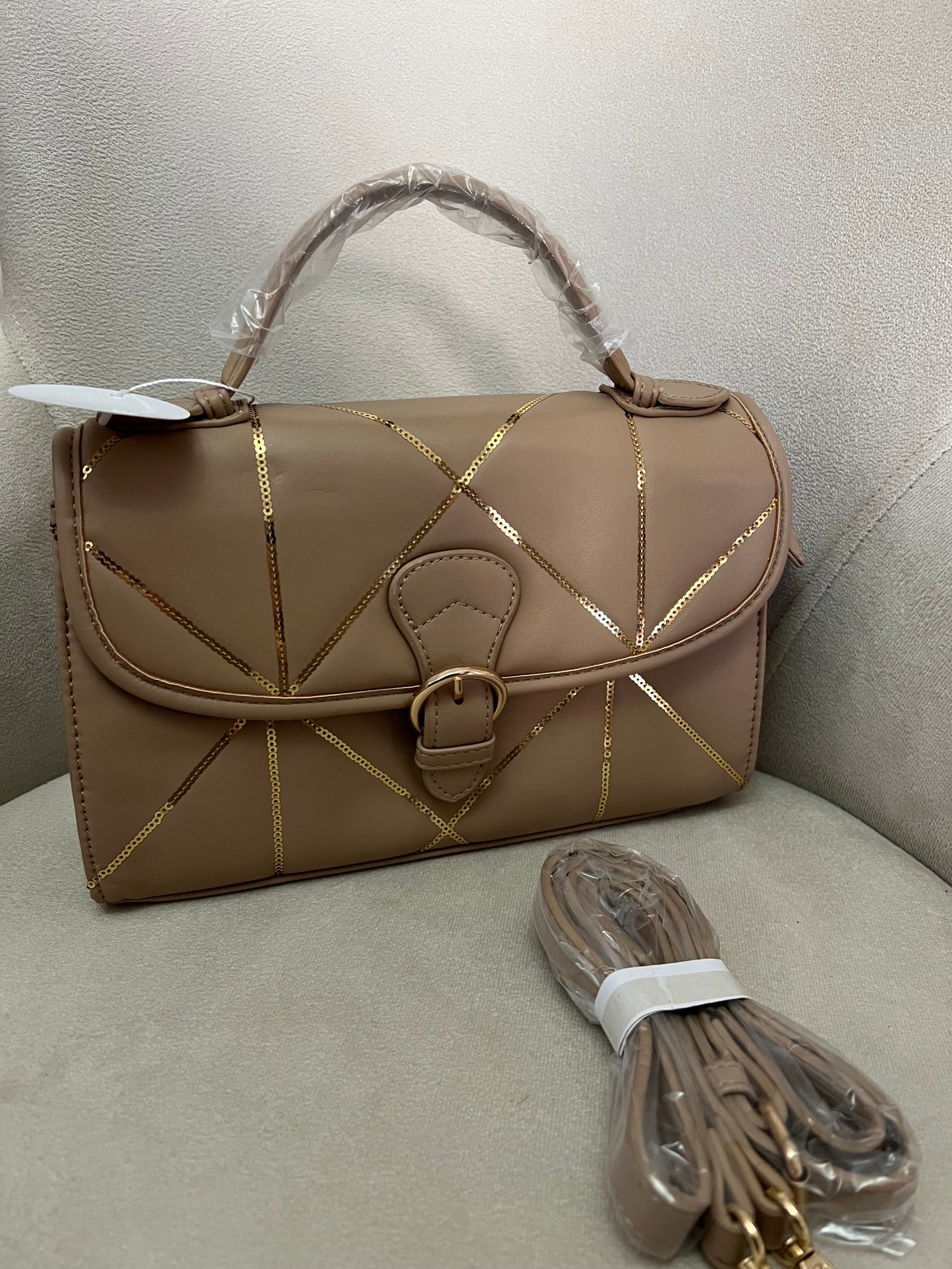 Bolso beige con detalles dorados.