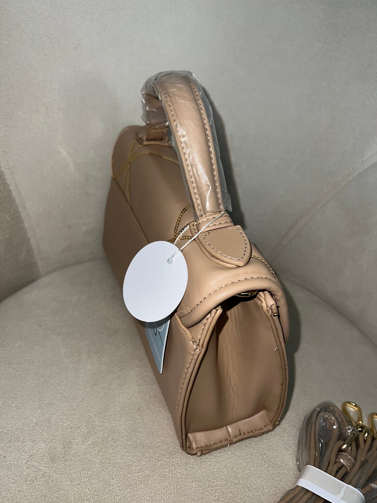 Bolso beige con detalles dorados.